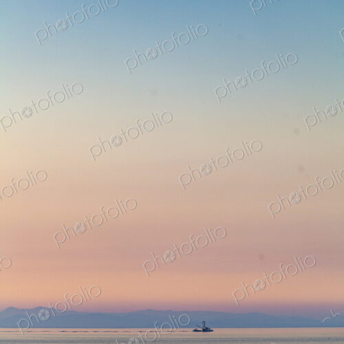 A purse seiner fishing vessel at dusk on the Strait of Juan de Fuca trailing a large net. A purse seiner fishing vessel at dusk on the Strait of Juan de Fuca trailing a large net.