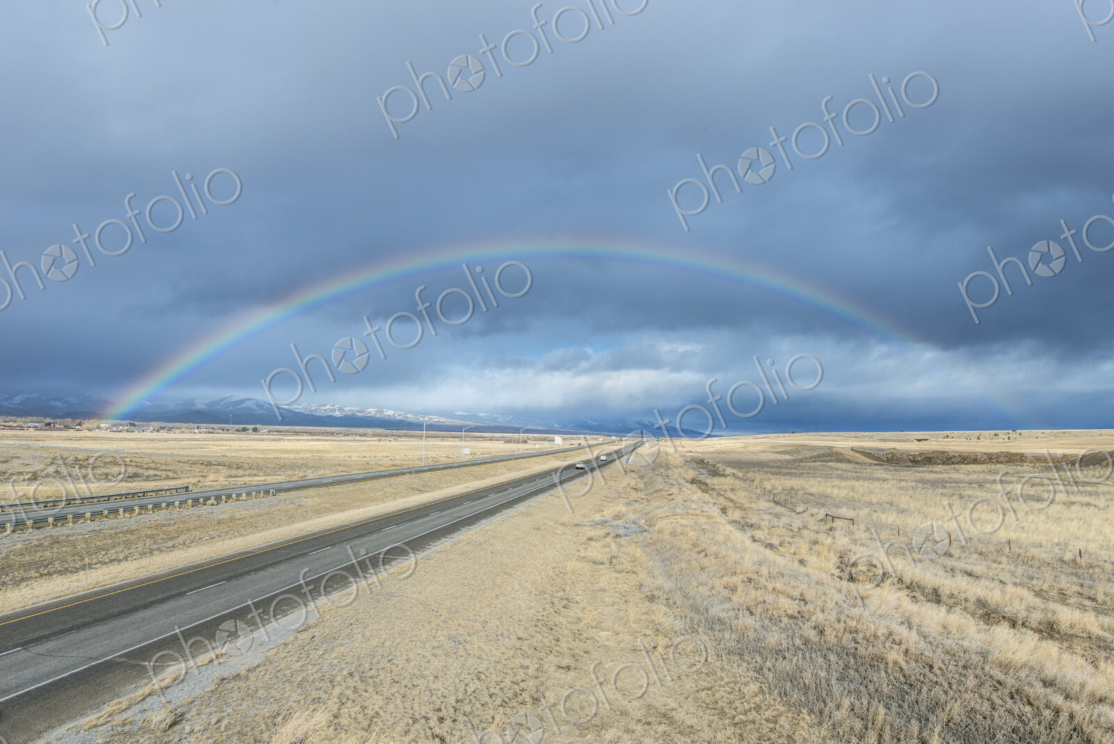 A rainbow in the sky above the highway I-90, a flat landscape and highway through…