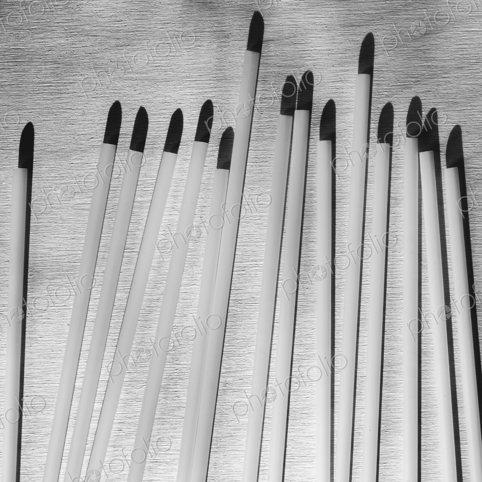 A range of white plastic drinking straws with black tips.