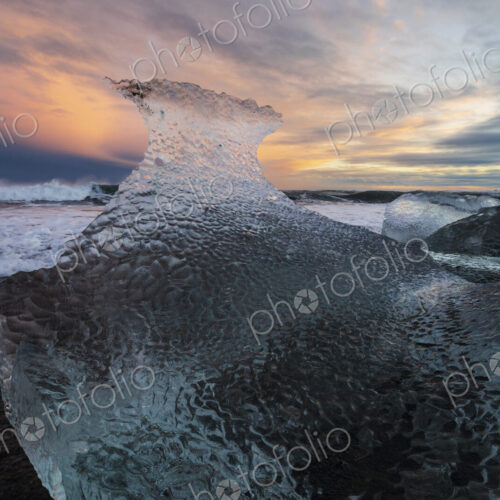 A receding wave and a chunk of calved Ice on the black sand beach at sunset A receding wave and a chunk of calved Ice on the black sand beach at sunset