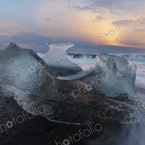 A receding wave and a chunk of calved Ice on the black sand beach at sunset A receding wave and a chunk of calved Ice on the black sand beach at sunset