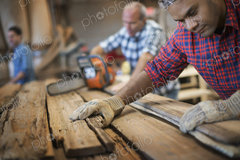 A reclaimed lumber workshop. A group of people working. A man measuring and checking…