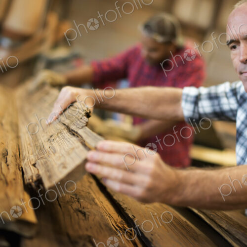 A reclaimed lumber workshop. A group of people working. A man measuring and checking… A reclaimed lumber workshop. A group of people working. A man measuring and checking…