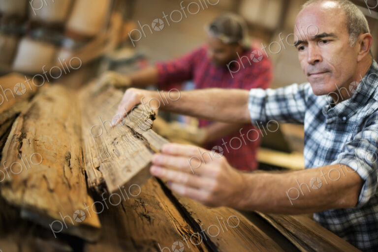 A reclaimed lumber workshop. A group of people working. A man measuring and checking…