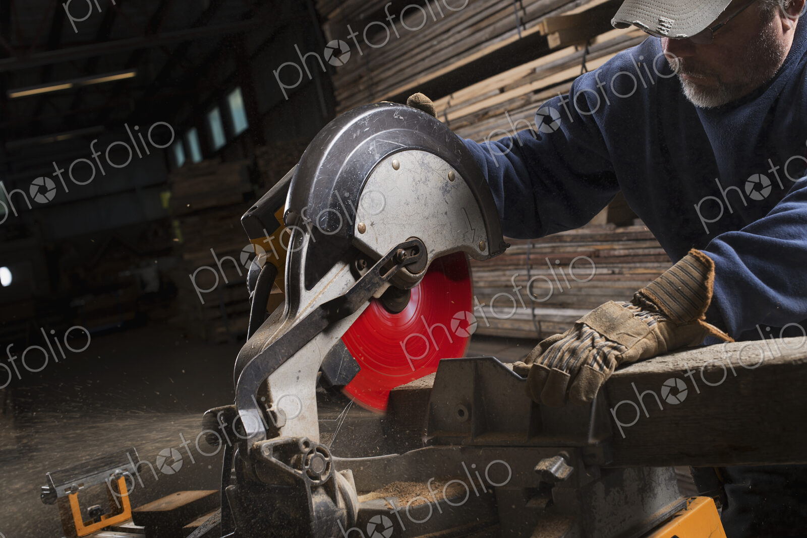A reclaimed lumber workshop. A man in protective eye goggles using a circular saw to…