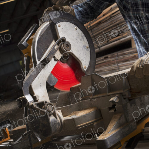 A reclaimed lumber workshop. A man in protective eye goggles using a circular saw to… A reclaimed lumber workshop. A man in protective eye goggles using a circular saw to…