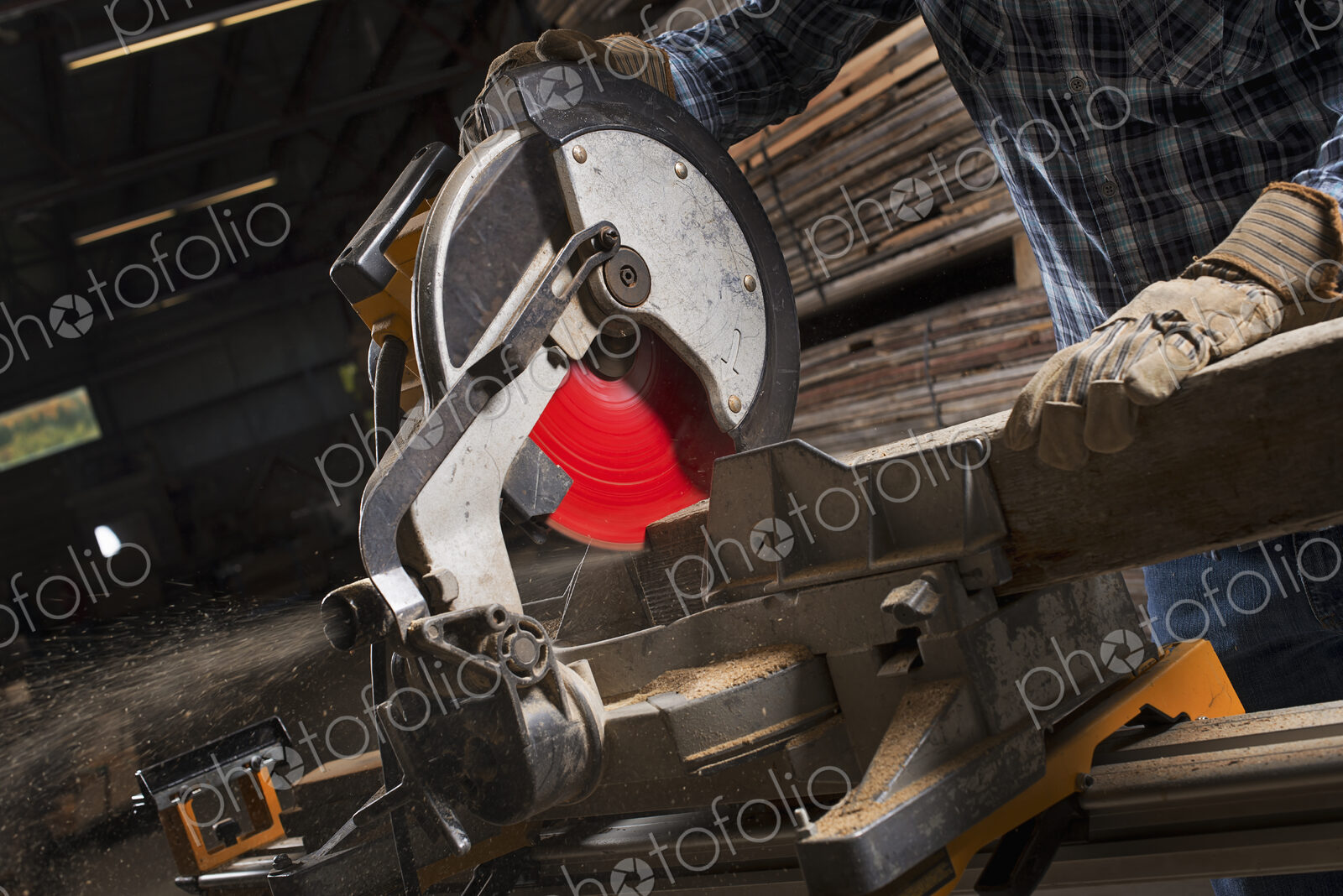 A reclaimed lumber workshop. A man in protective eye goggles using a circular saw to…