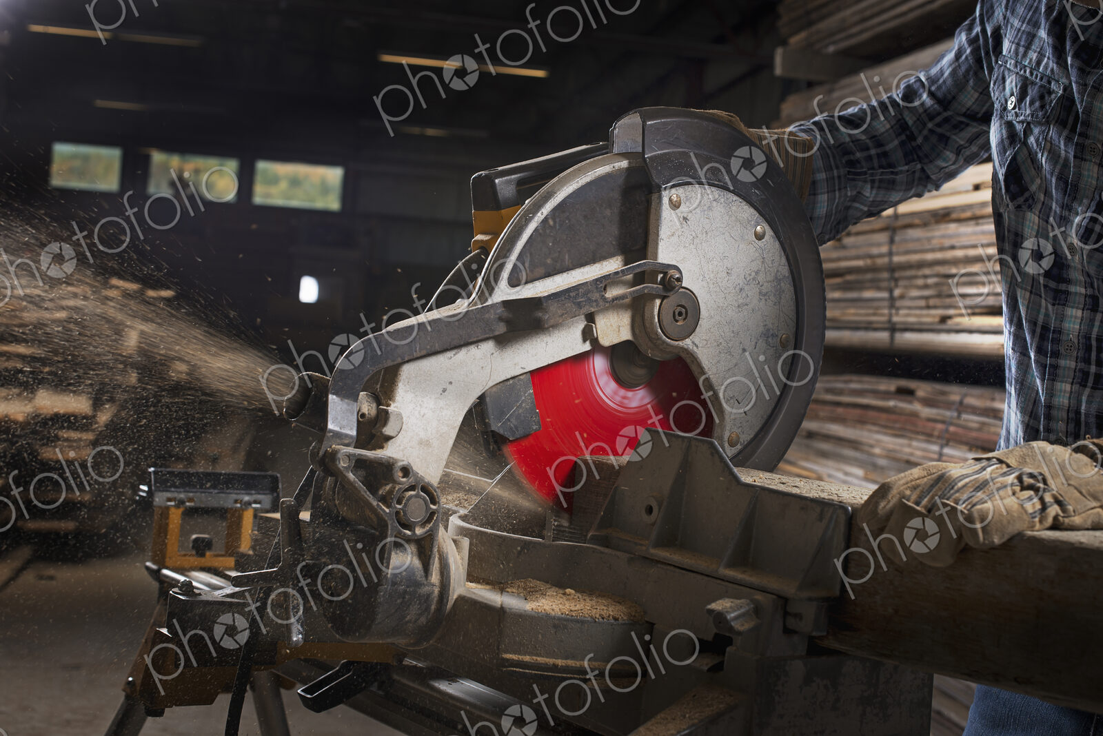 A reclaimed lumber workshop. A man in protective eye goggles using a circular saw to…