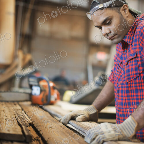 A reclaimed lumber workshop. A man measuring and checking planks of wood for re-use… A reclaimed lumber workshop. A man measuring and checking planks of wood for re-use…