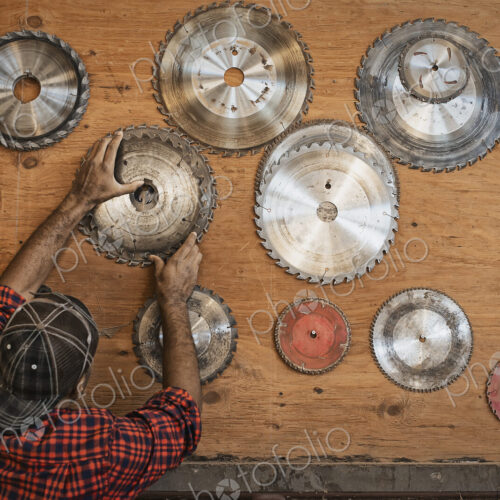 A reclaimed lumber workshop. A man reaching up to a storage board for circular saw… A reclaimed lumber workshop. A man reaching up to a storage board for circular saw…