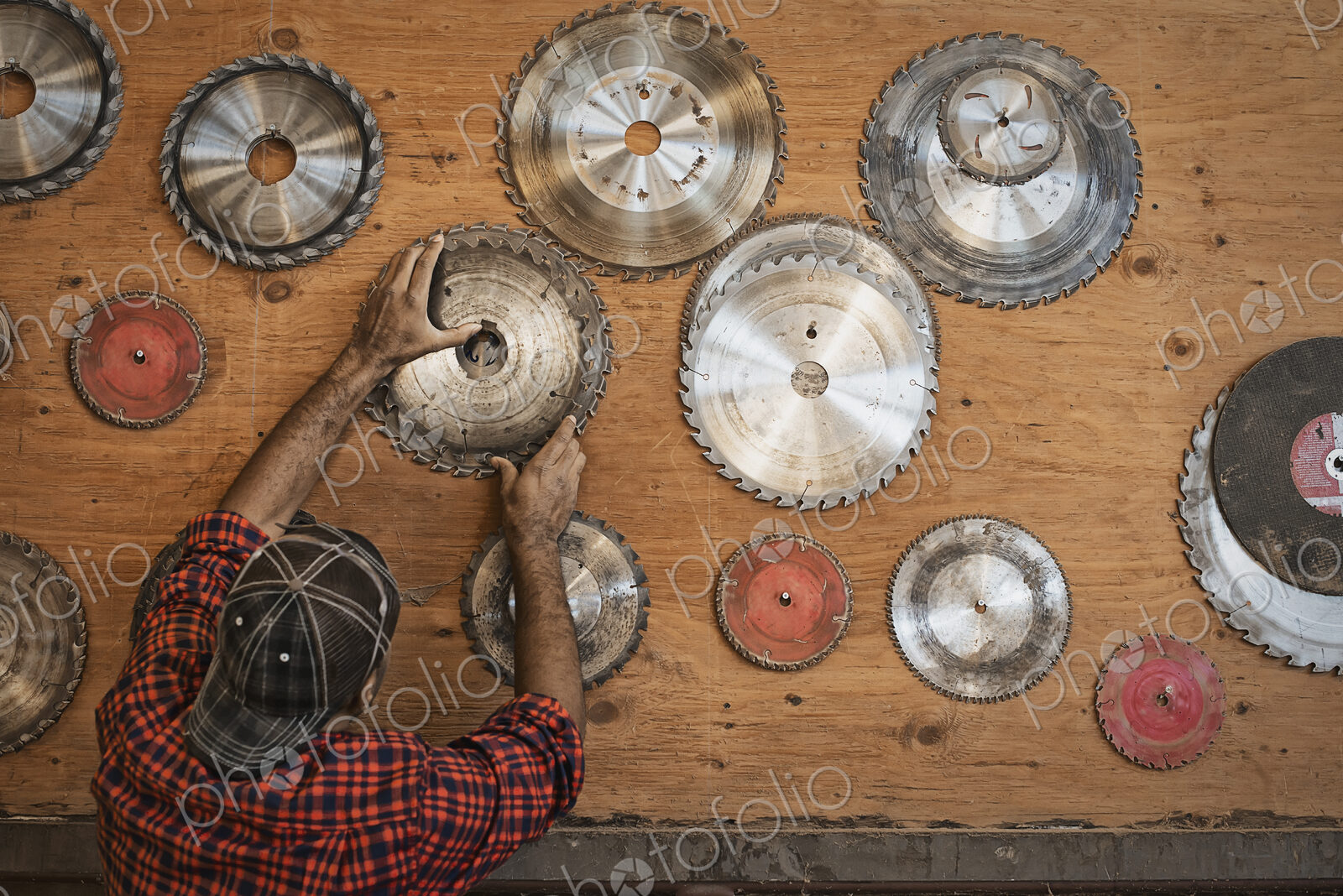 A reclaimed lumber workshop. A man reaching up to a storage board for circular saw…