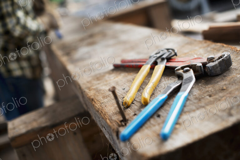 A reclaimed lumber workshop. A person at a workbench, and tools, grippers and pliers…