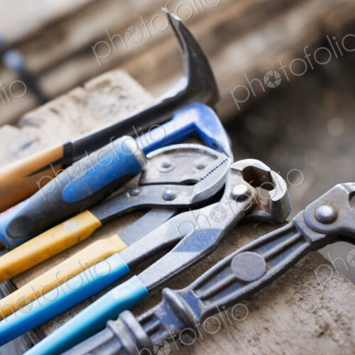 A reclaimed lumber workshop. A range of pliers and chisels on a plank of wood. A reclaimed lumber workshop. A range of pliers and chisels on a plank of wood.