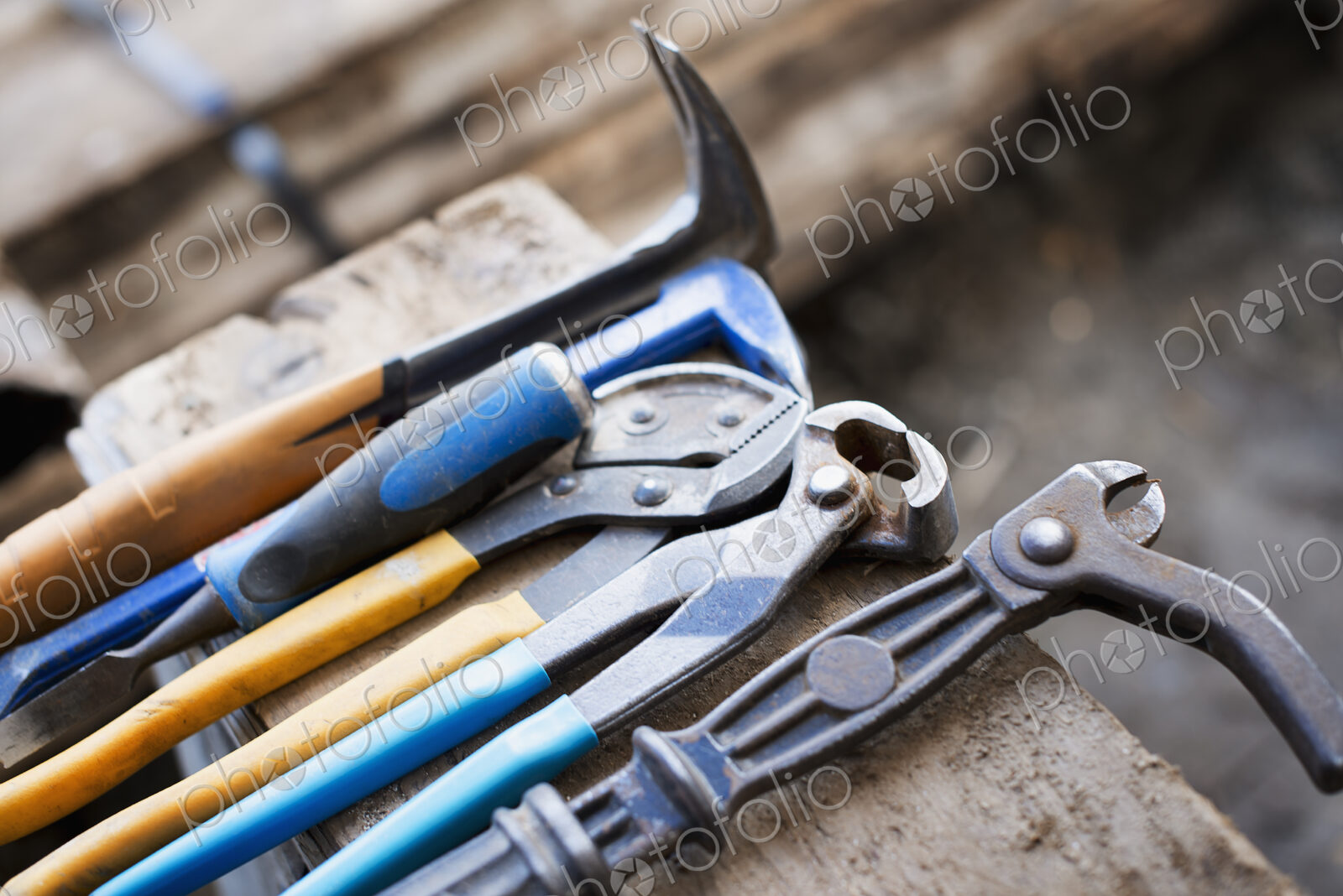 A reclaimed lumber workshop. A range of pliers and chisels on a plank of wood.