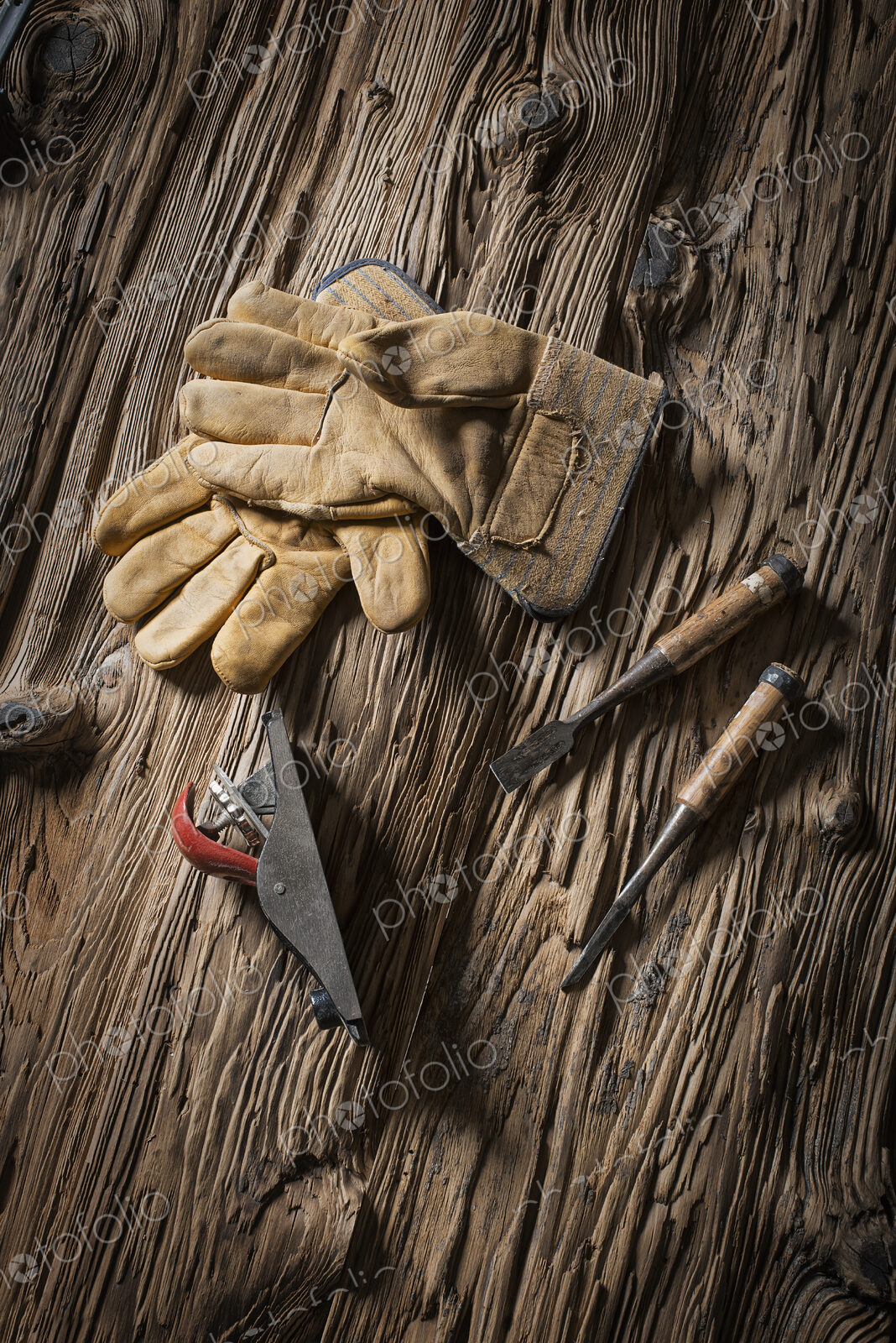 A reclaimed lumber yard workshop. A pair of leather working gloves, and handheld…