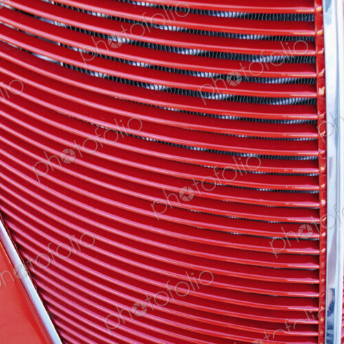 A red car, classic design with radiator grille on the bonnet.