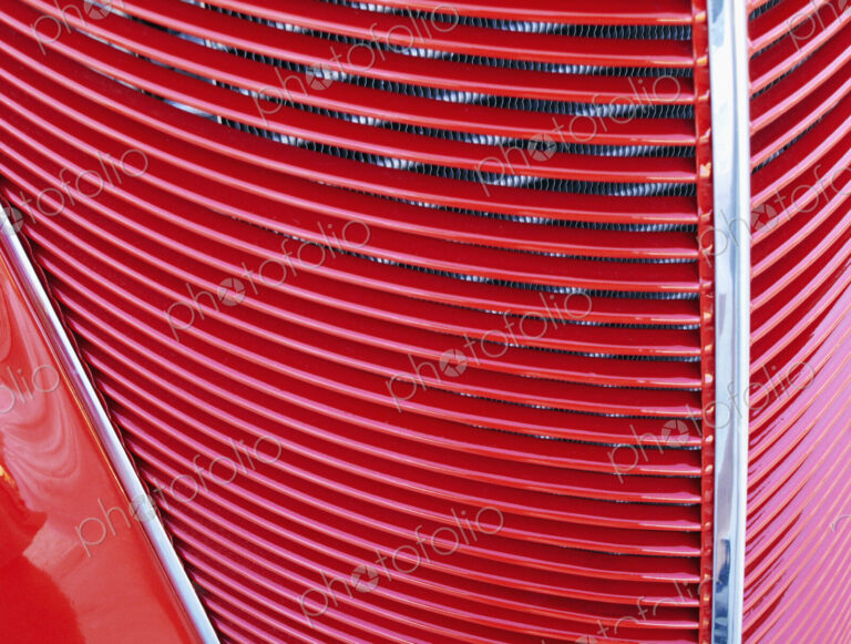 A red car, classic design with radiator grille on the bonnet.