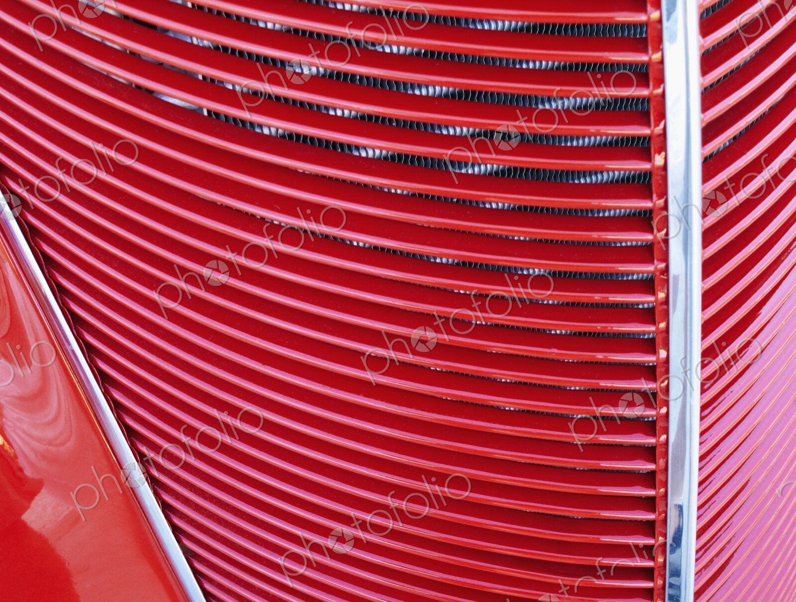 A red car, classic design with radiator grille on the bonnet.