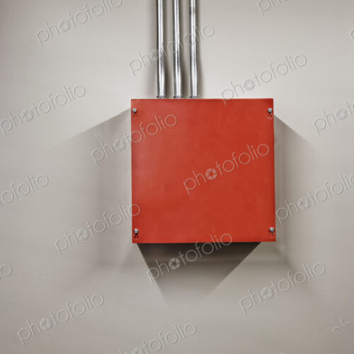 A red metal power junction box in a computer server farm. A red metal power junction box in a computer server farm.