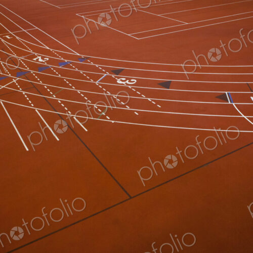 A red running track, athletics ground, a corner section of track marked with lanes