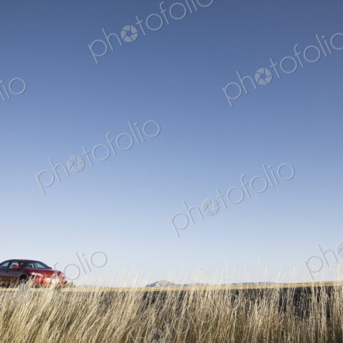 A red sedan parked along a highway in eastern Washington State, USA.