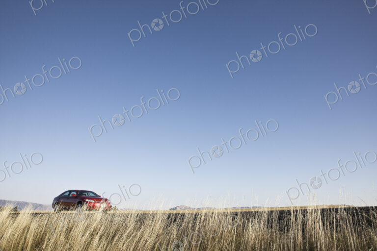 A red sedan parked along a highway in eastern Washington State, USA.