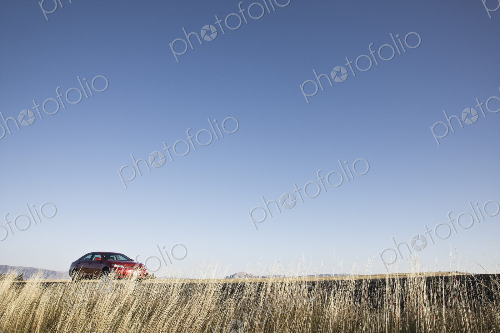 A red sedan parked along a highway in eastern Washington State, USA.