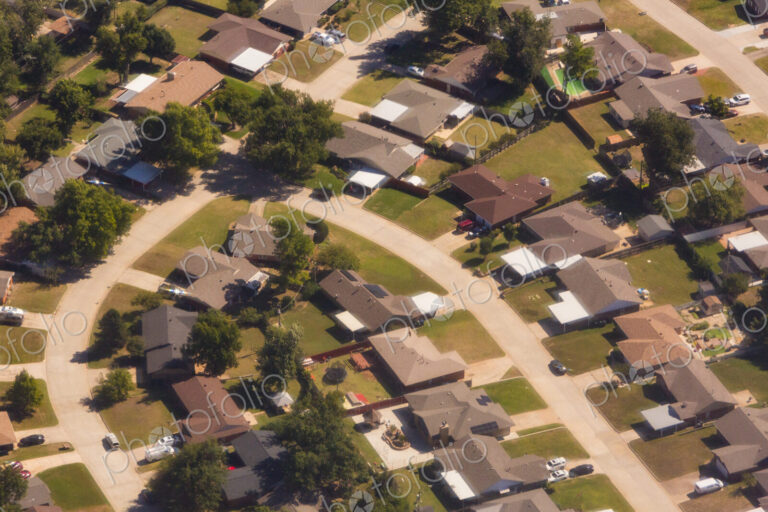 A residential area, an aerial view of the houses, layout and gardens and the roads.