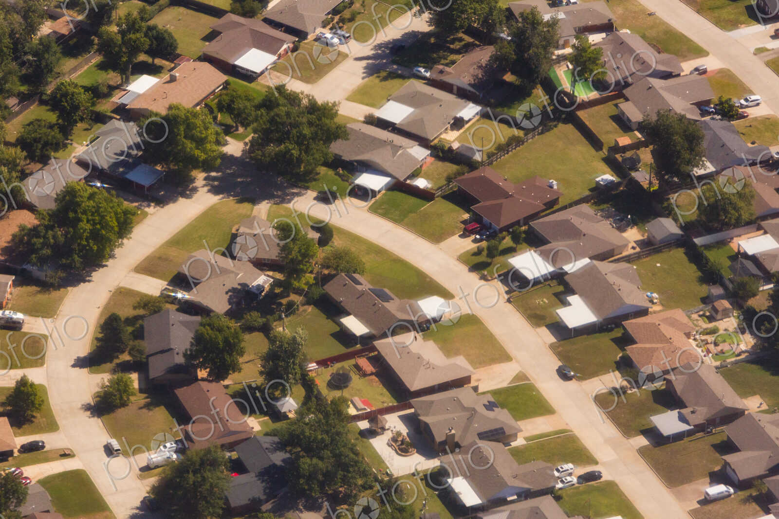 A residential area, an aerial view of the houses, layout and gardens and the roads.