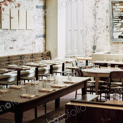 A restaurant with long narrow tables and chairs laid for a meal. A large chalk menu board. A restaurant with long narrow tables and chairs laid for a meal. A large chalk menu board.