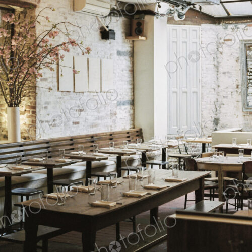 A restaurant with long narrow tables and chairs laid for a meal. A large chalk menu board. A restaurant with long narrow tables and chairs laid for a meal. A large chalk menu board.