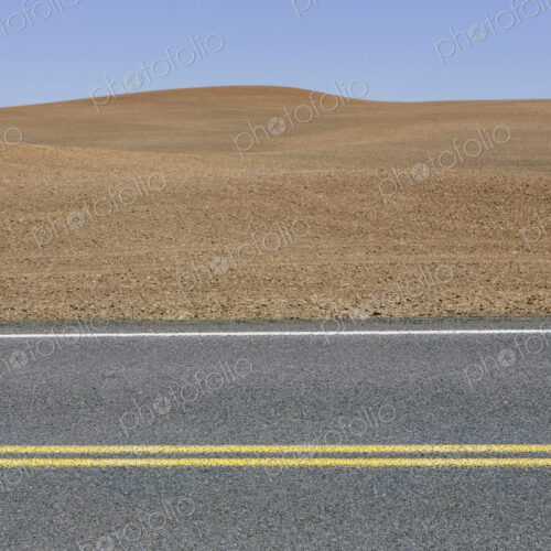 A road through the farming landscape of ploughed fields and farmland near Pullman,…