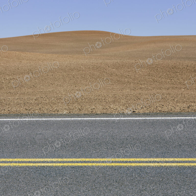 A road through the farming landscape of ploughed fields and farmland near Pullman,…