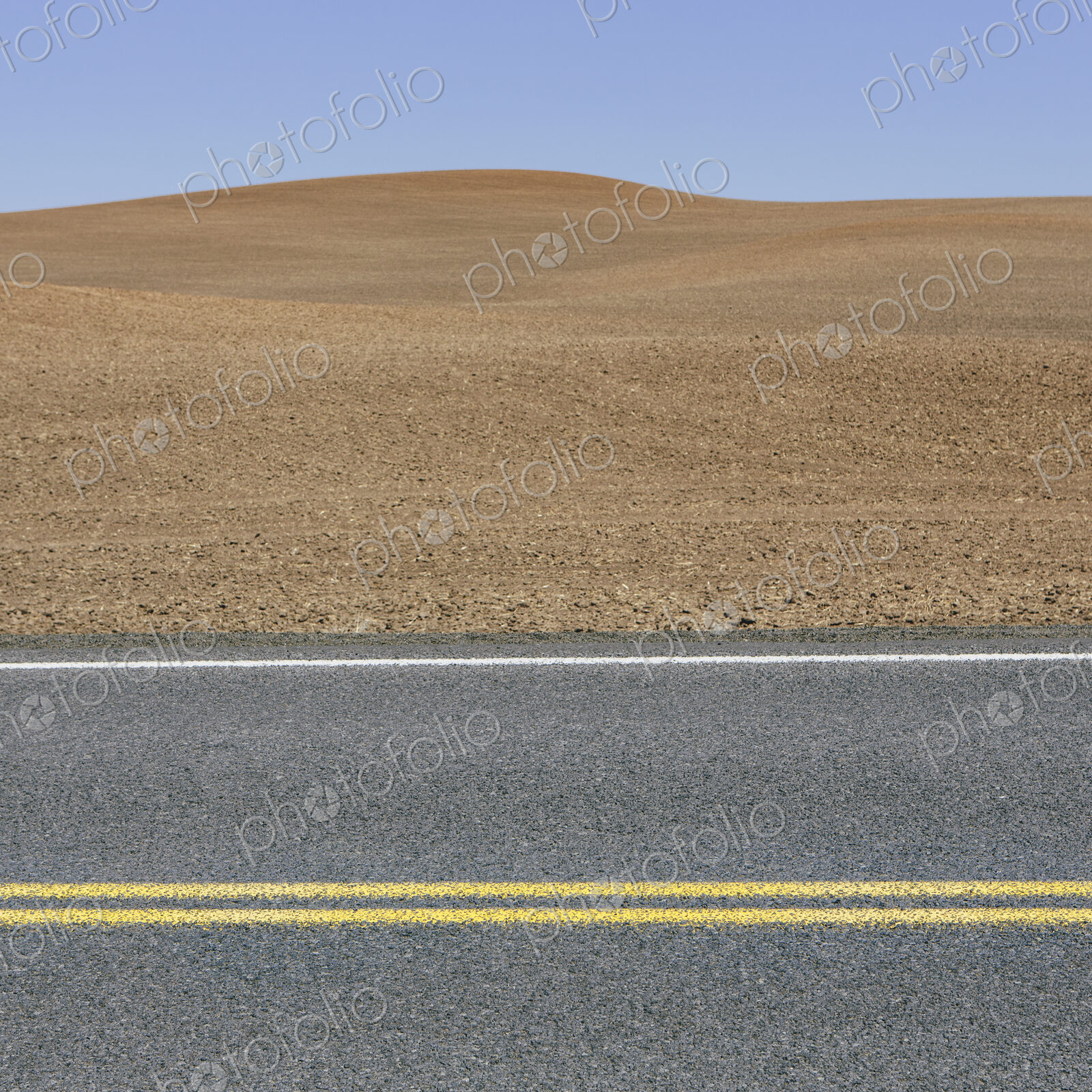 A road through the farming landscape of ploughed fields and farmland near Pullman,…