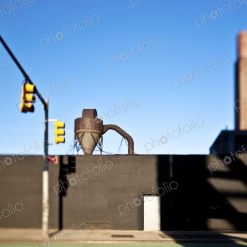 A road with traffic lights and view of an industrial hopper in the docks.