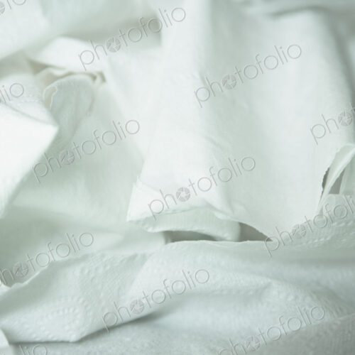 A roll of toilet paper, unwound and crumpled.
