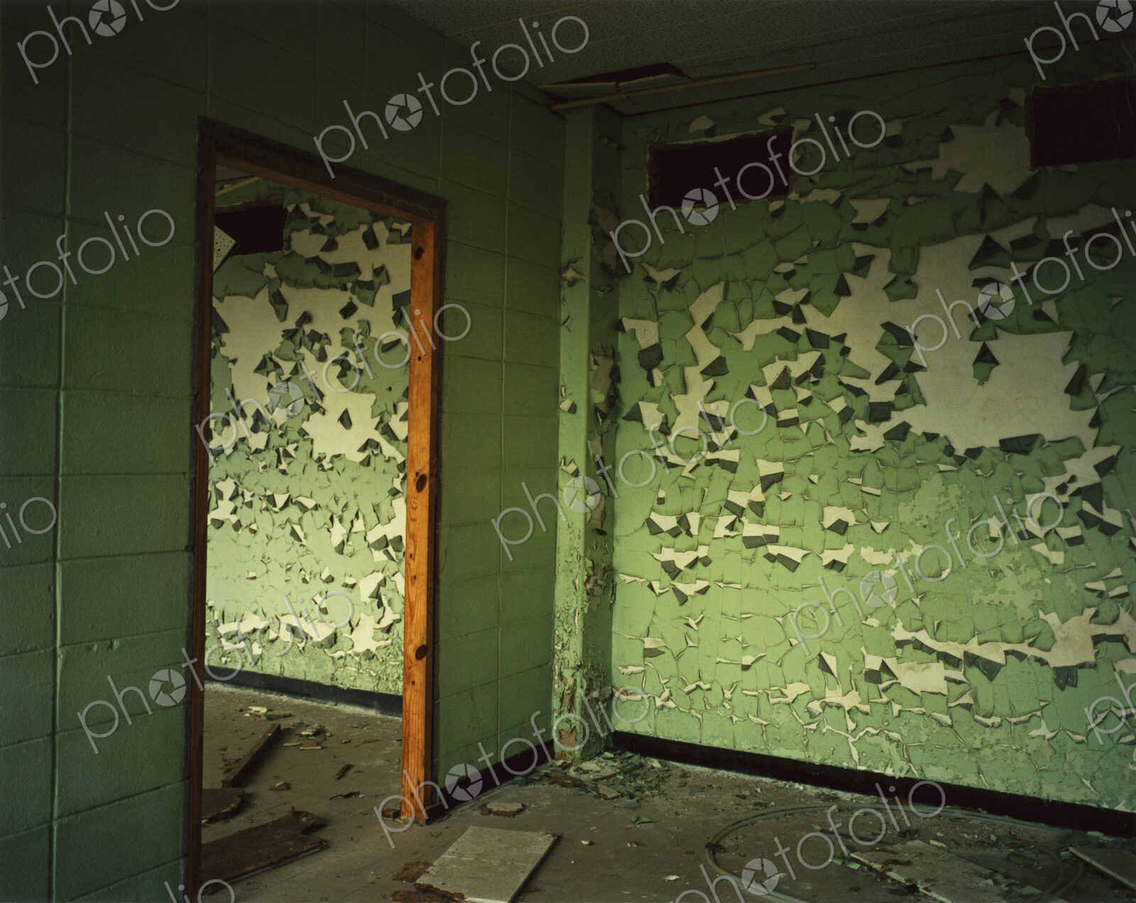 A room with peeling green paint on the walls. A deserted building.