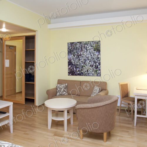 A room with sofa and chairs, television, storage and a desk