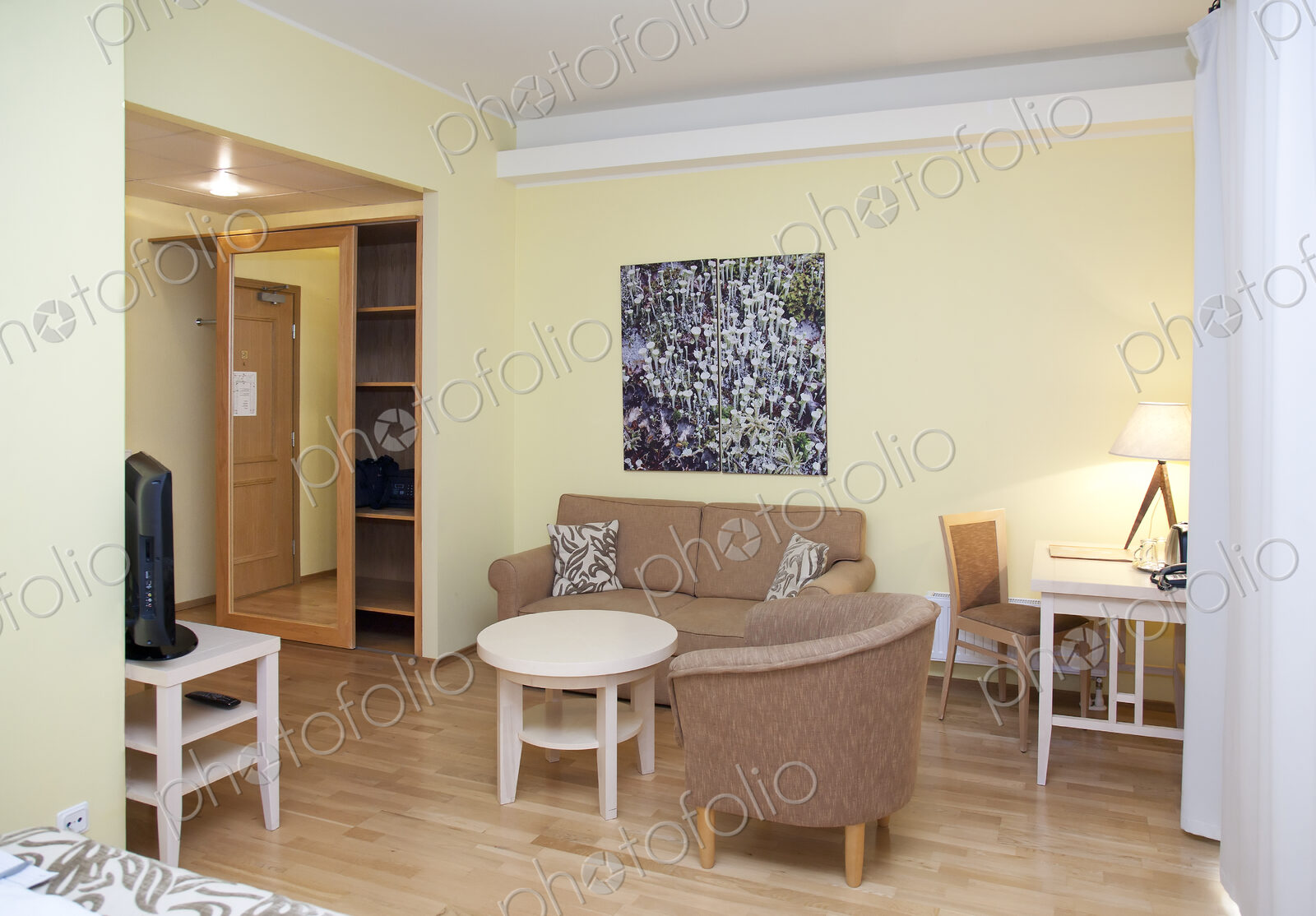 A room with sofa and chairs, television, storage and a desk
