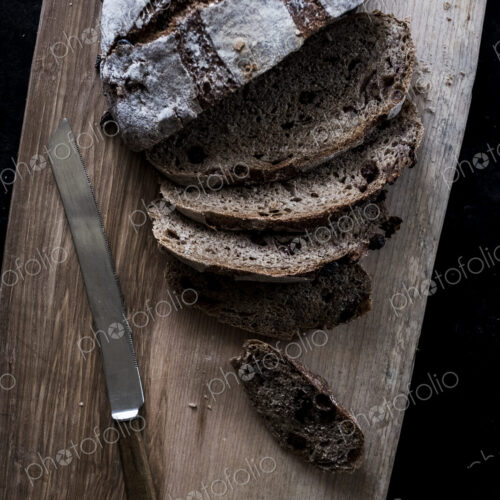 A round loaf of brown bread on a bread board partly sliced. A round loaf of brown bread on a bread board partly sliced.
