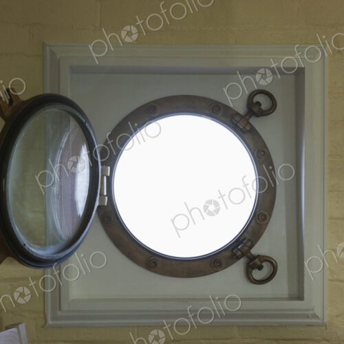 A round window, metal frame and a round glass porthole, open. A round window, metal frame and a round glass porthole, open.