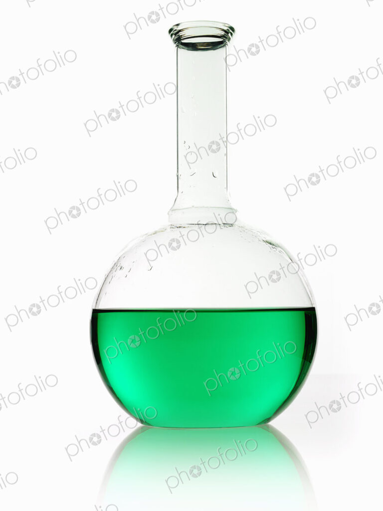 A rounded glass scientific chemical flask with a long funnel neck, holding green liquid.