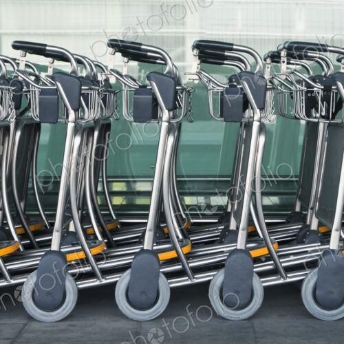 A row of empty luggage carts at an airport. A row of empty luggage carts at an airport.