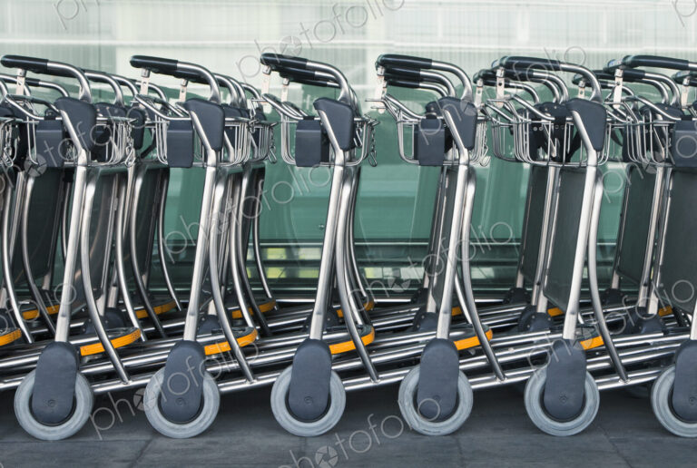 A row of empty luggage carts at an airport.