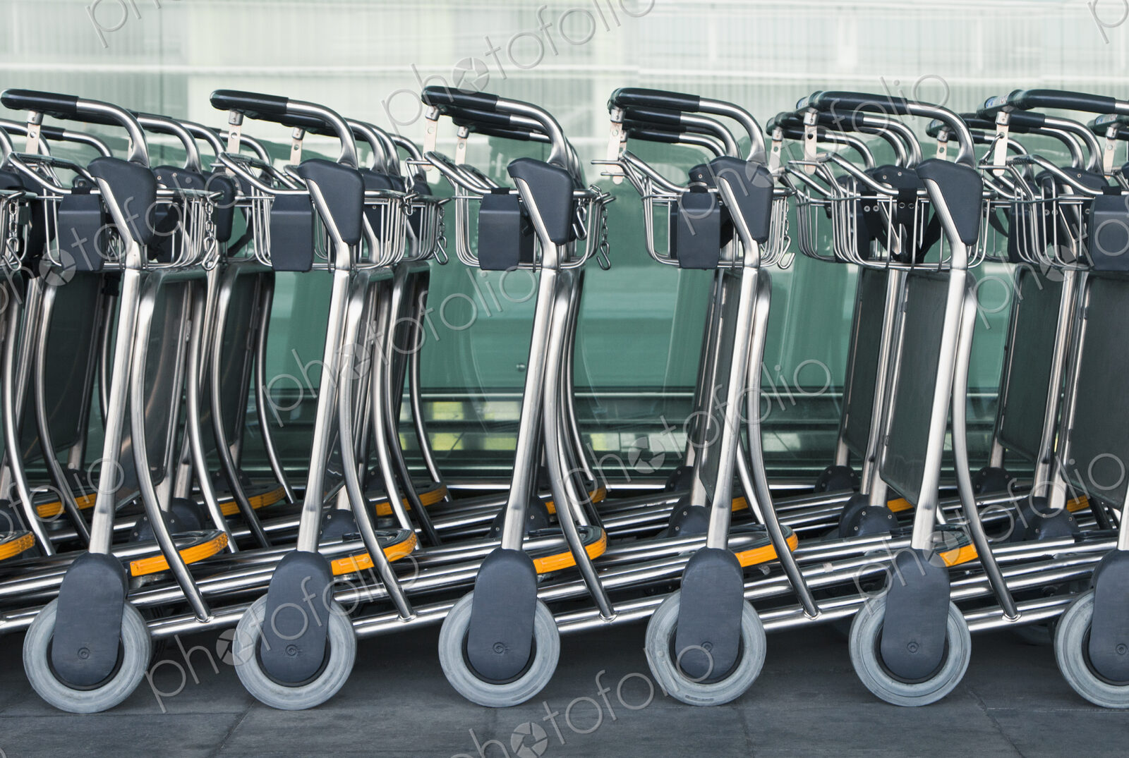 A row of empty luggage carts at an airport.