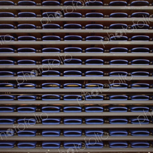 A row of folded seats on shelves in an indoor sports venue.
