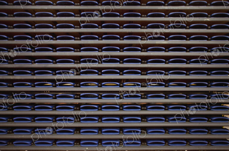 A row of folded seats on shelves in an indoor sports venue.