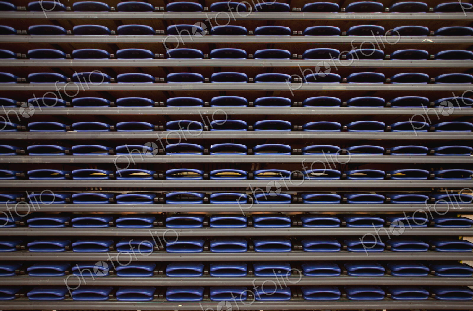 A row of folded seats on shelves in an indoor sports venue.