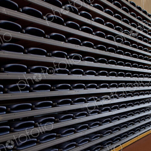 A row of folded seats,in an indoor sports venue. Stacked up and folded away., A row of folded seats,in an indoor sports venue. Stacked up and folded away.,