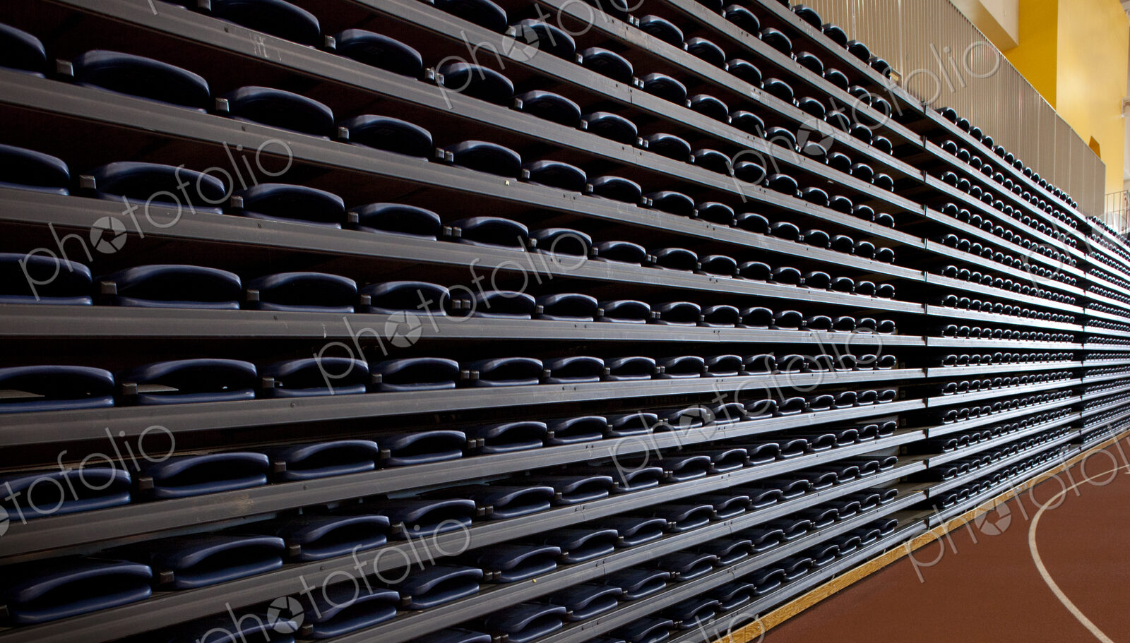 A row of folded seats,in an indoor sports venue. Stacked up and folded away.,
